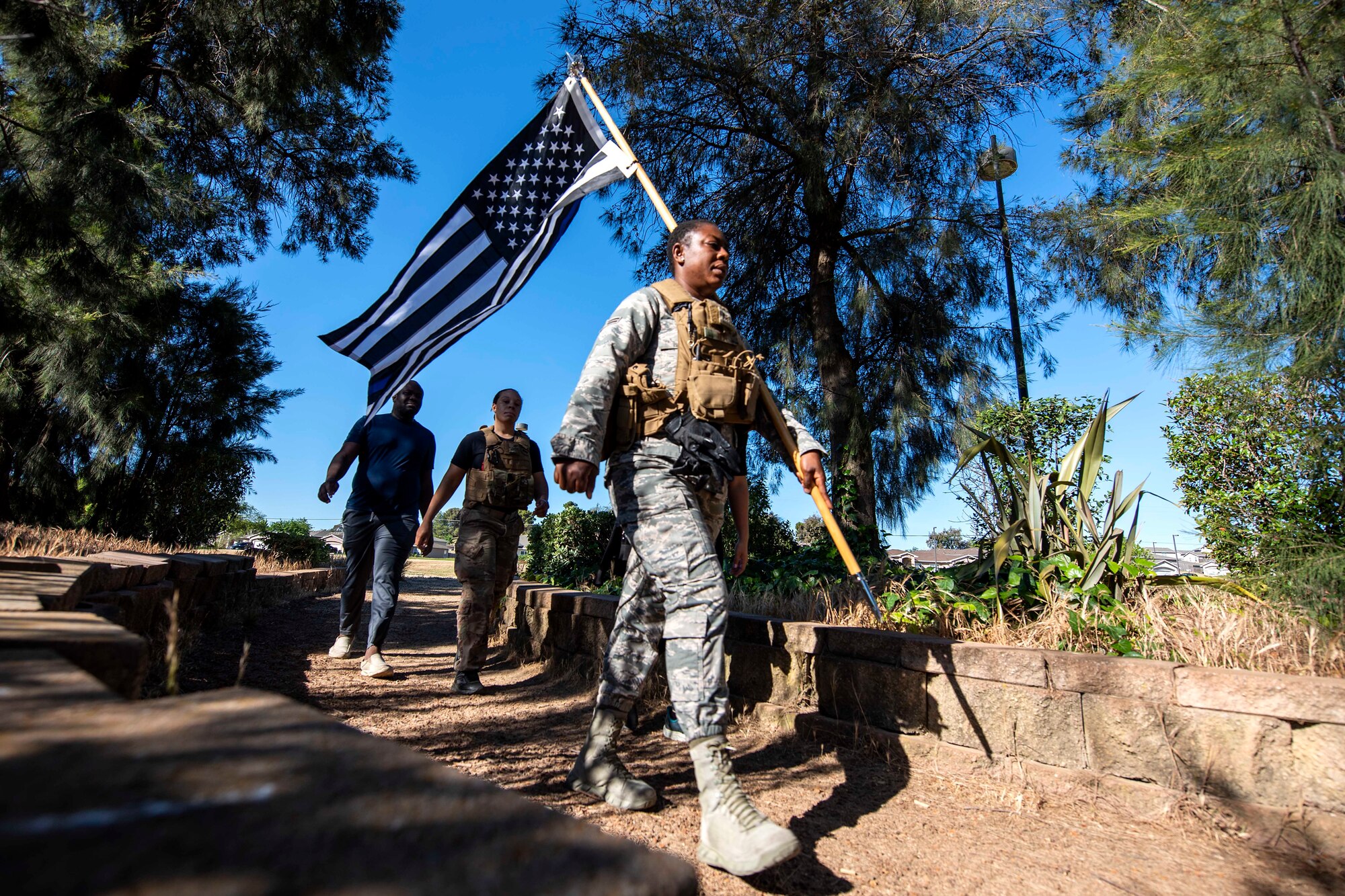 Photo of service members marching with a guidon.