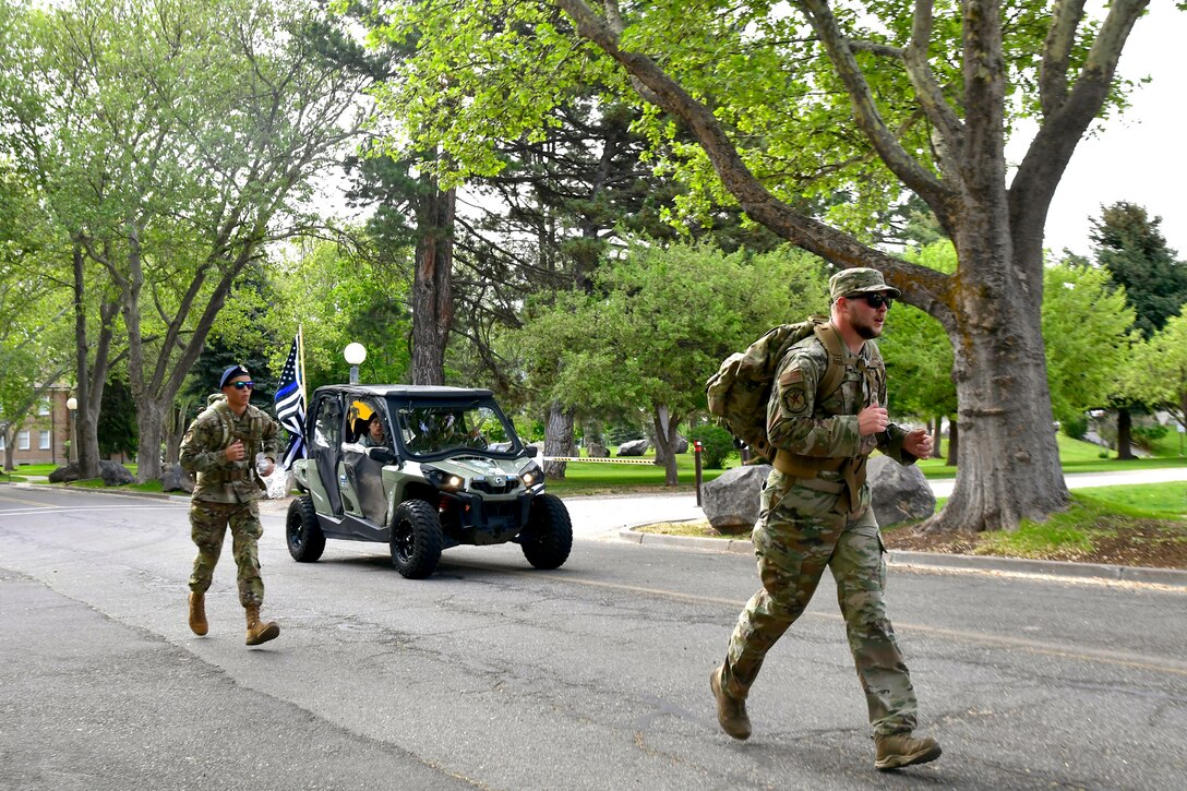 75th Security Forces Squadron Defenders during a ruck march. Airmen riding in a side-by-side ATV appears in the background.