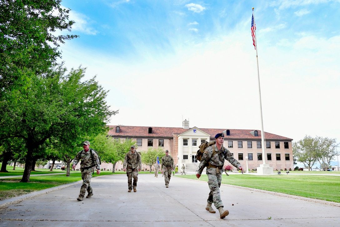 75th Security Forces Squadron Defenders walking away from the 75th Air Base Wing Headquarters building. The American flag also appears in the background.