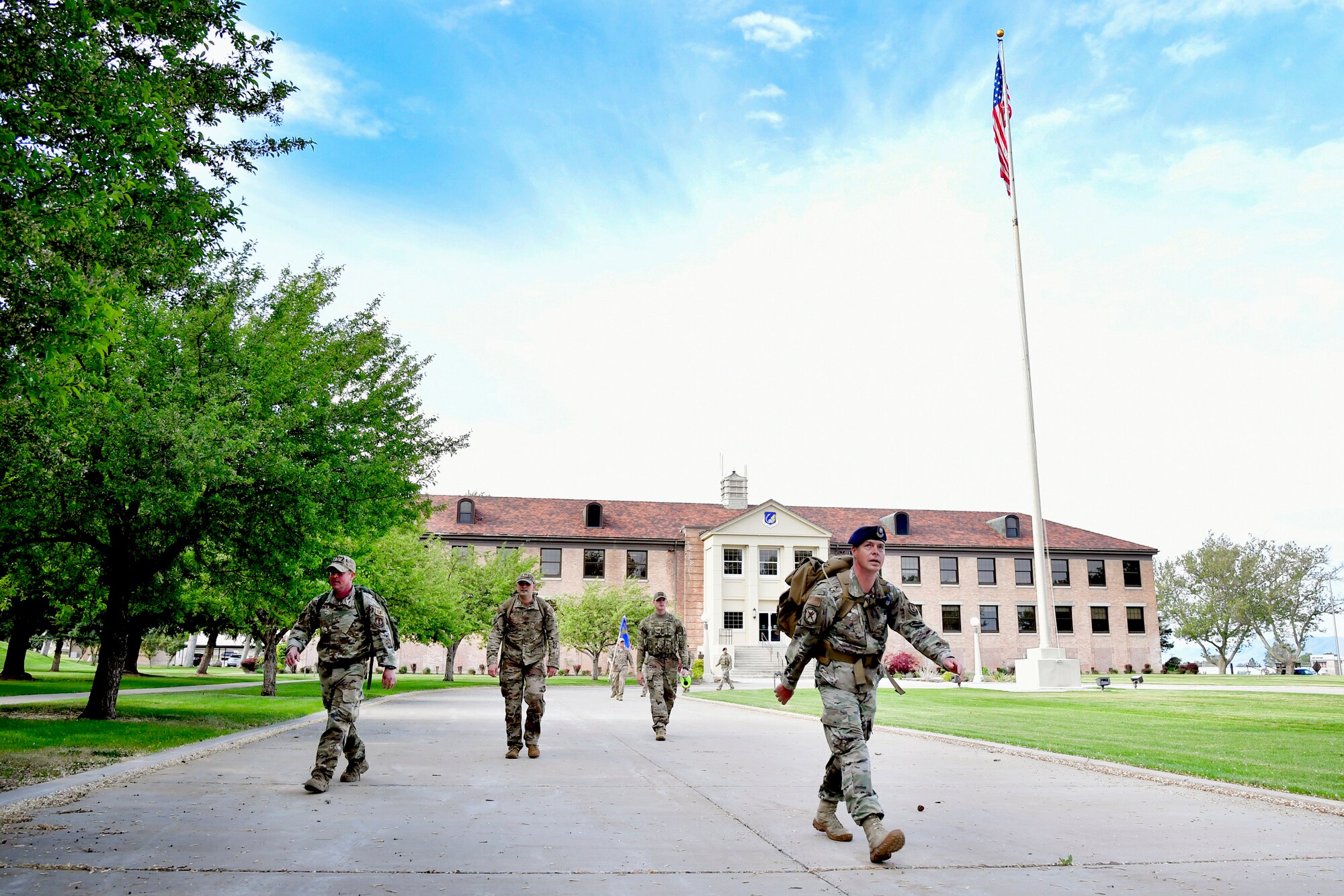 75th Security Forces Squadron Defenders walking away from the 75th Air Base Wing Headquarters building. The American flag also appears in the background.