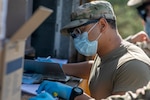 North Carolina Army National Guard Sgt. Michael Lucas, assigned to the 1450th Transportation Company, checks a list of equipment while delivering protective equipment to medical facilities at a distribution site in Louisburg, North Carolina, May 15, 2020.