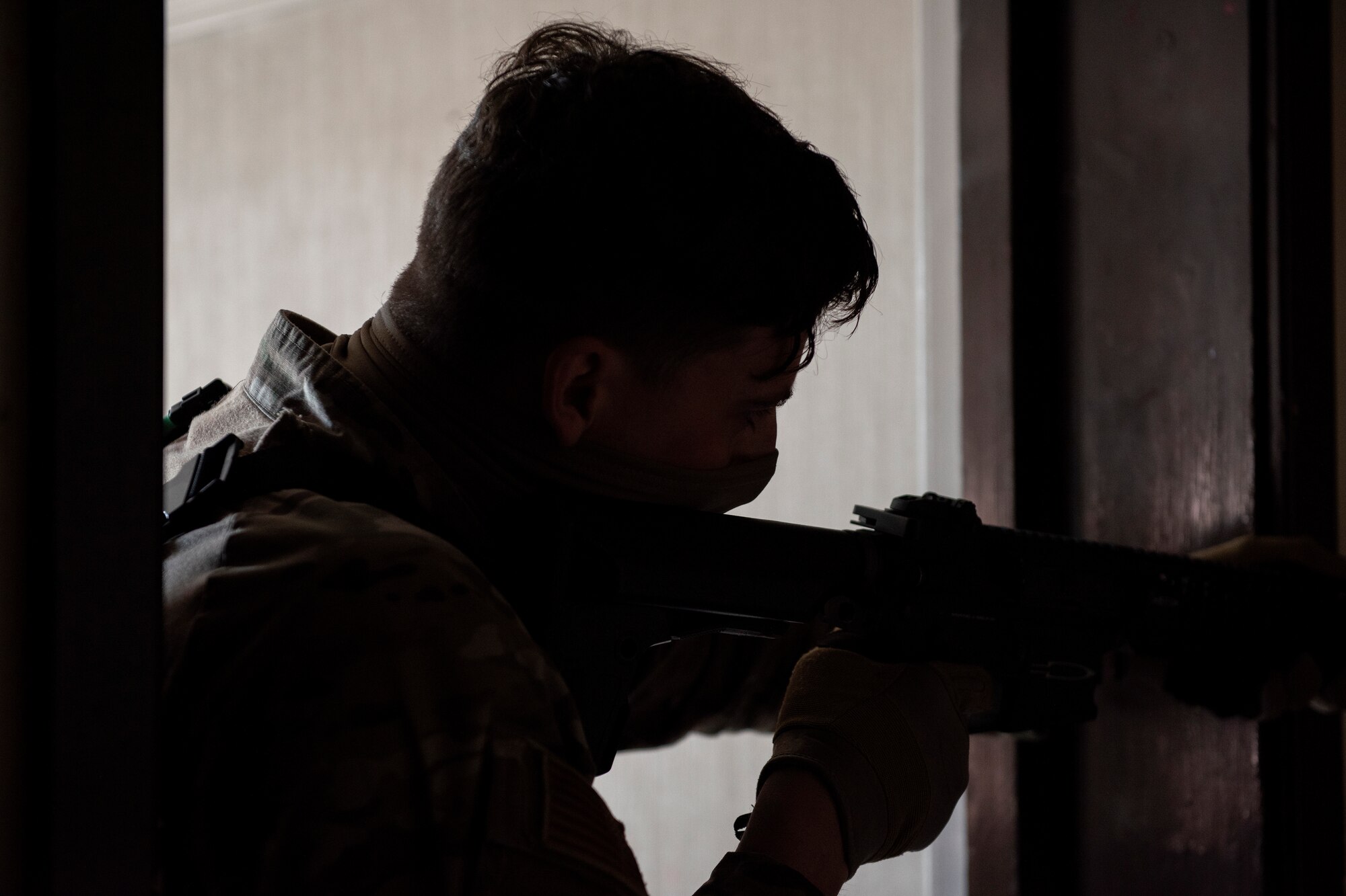 A defender from the 48th Security Forces Squadron checks around a corner for opposing forces in the shoot house during a close-quarters combat capture the flag challenge for National Police Week at Royal Air Force Feltwell, England, May 13, 2020. The challenge was one of several events during National Police Week, an annual time of remembrance to commemorate those law enforcement officers who have lost their lives in the line of duty. (U.S. Air Force photo by Airman 1st Class Jessi Monte)
