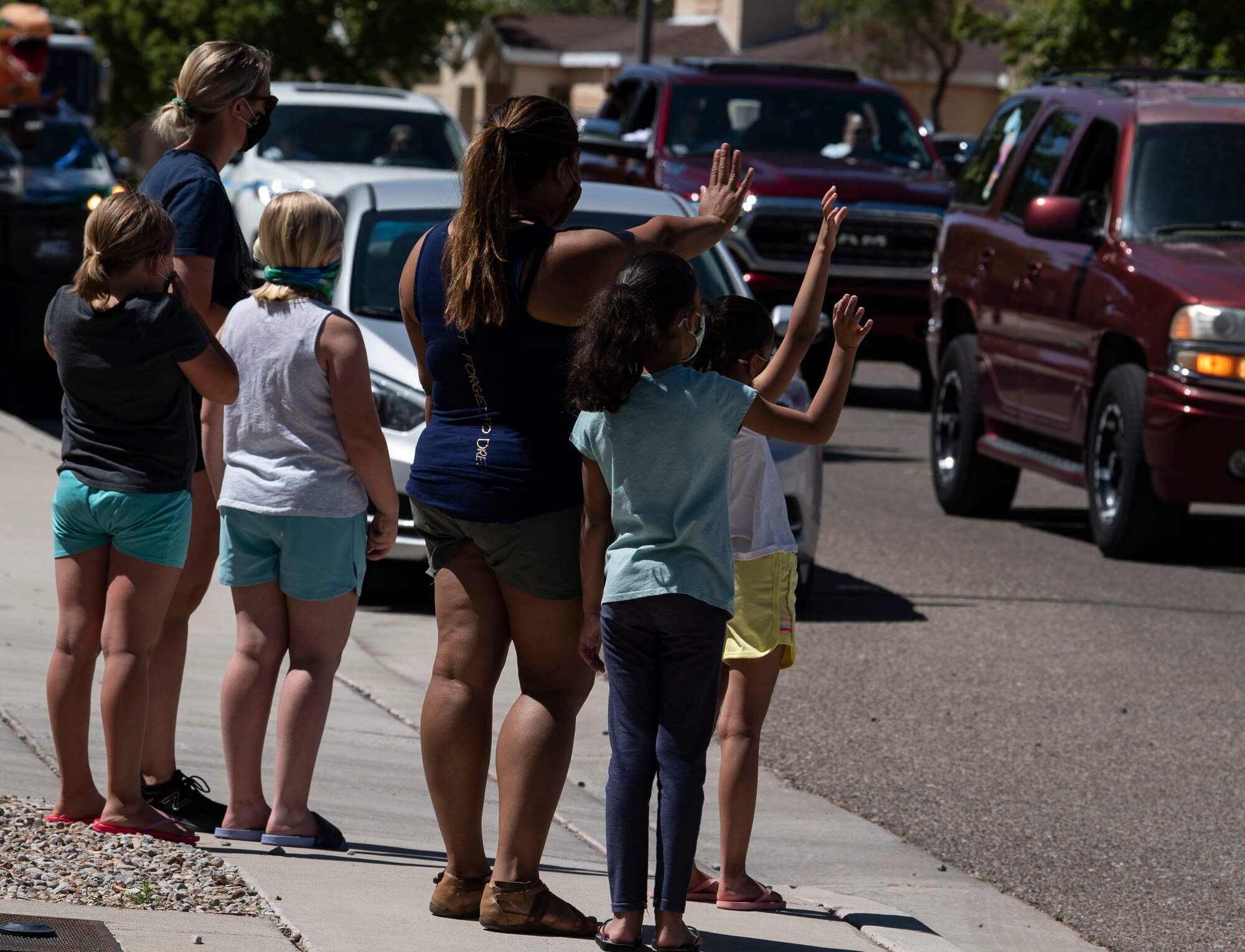Families wave as a parade passes by.