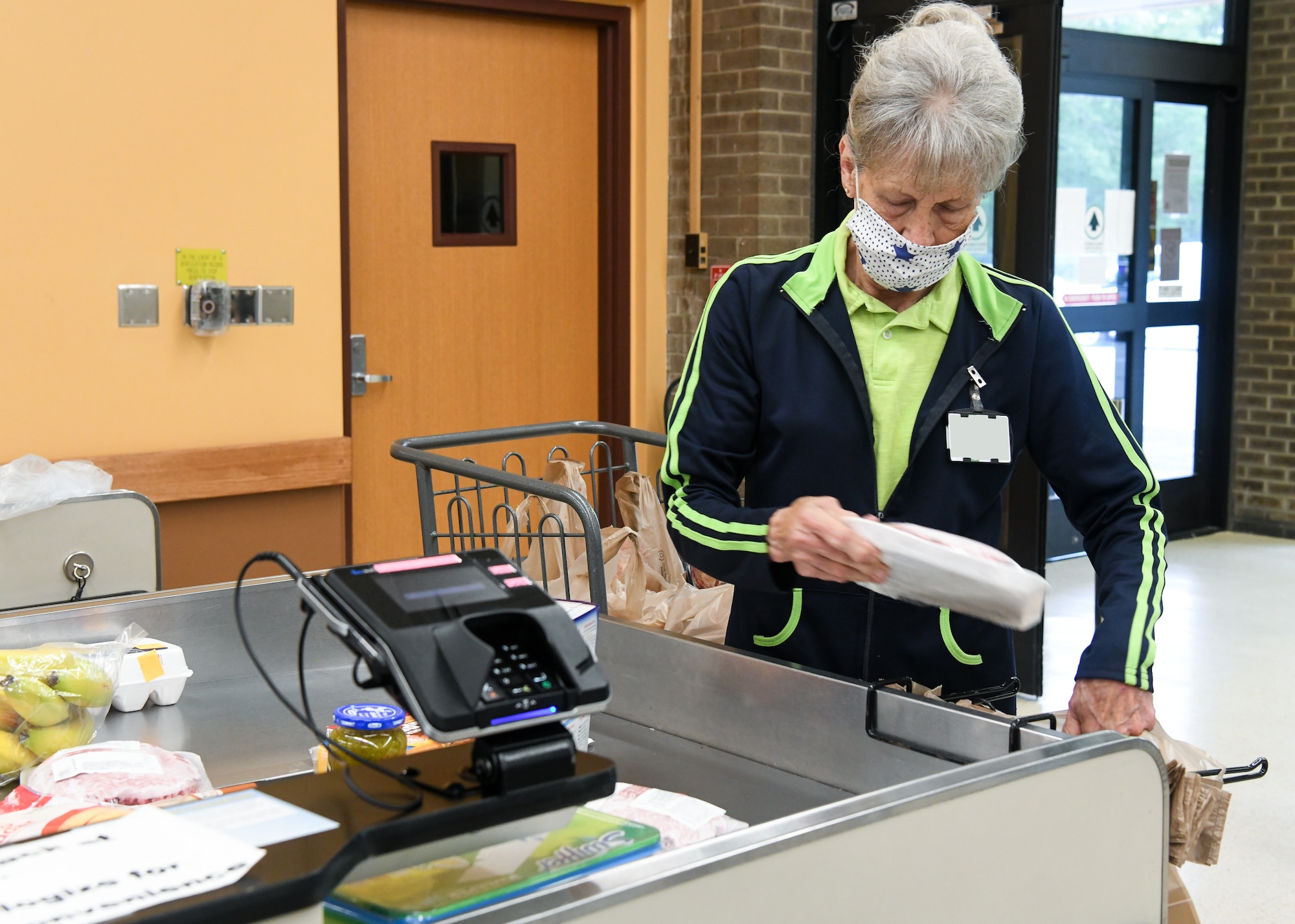 Bagger Mary Cathey bags a customer's purchases, May 5, 2020, at the Arnold Air Force Base Commissary, while taking measures to reduce the risk of coronavirus transmission. The Arnold Air Force Base Commissary and Base Exchange have remained open to serve their customers throughout the coronavirus crisis. (U.S. Air Force photo by Jill Pickett) (This image was altered by obscuring a badge for security purposes.)
