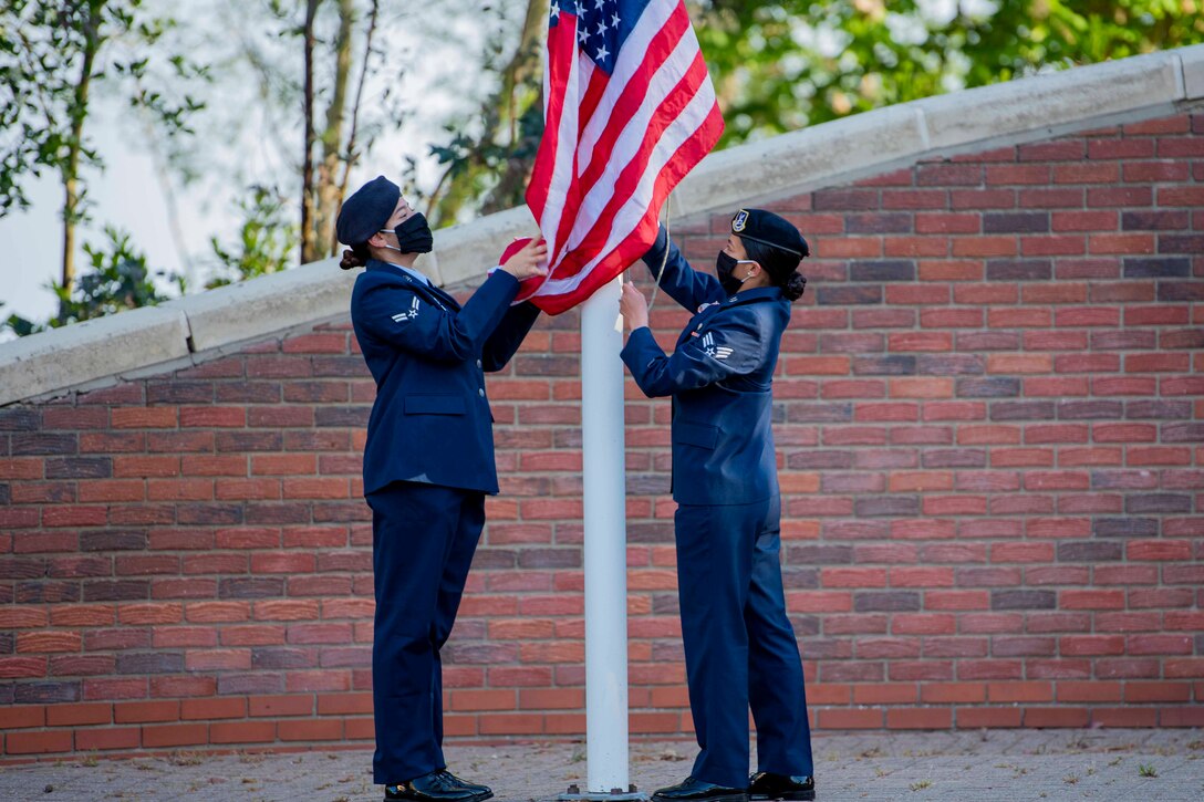 Two airmen raise an American flag.