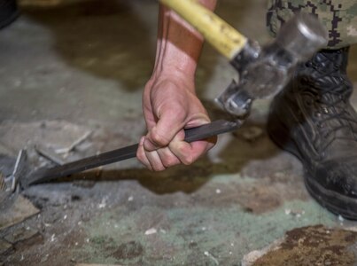 Aviation Boatswain's Mate (Fuel) Samuel Green, from Bellflower, California, removes deck material aboard the aircraft carrier USS George H.W. Bush (CVN 77).