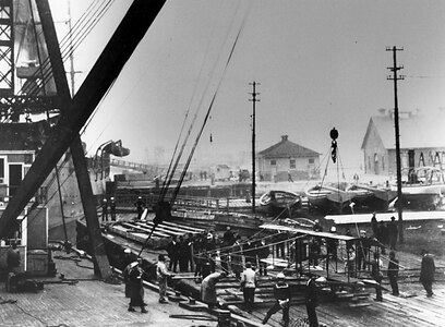 In this file photo provided by the U.S. Naval Historical Center taken in November 1910, a floating crane from Norfolk Naval Shipyard lifts a Curtiss Model D biplane to the deck of the Chester-class cruiser USS Birmingham (CL 2). Civilian aviator Eugene B. Ely flew the plane off Birmingham on Nov. 14, 1910, the first aircraft launch from a warship.