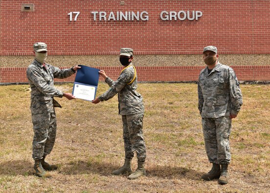 U.S. Air Force Col. Thomas Coakley, 17th Training Group commander, presents the 17 TRG Rope of the Month award to Airman 1st Class Stephanie Cates, 315th TRS student, at Brandenburg Hall on Goodfellow Air Force Base, Texas, May 15, 2020. Military Training Leaders present different ropes to Airmen who display exceptional qualities to lead their peers in various aspects of the training pipeline. (U.S. Air Force photo by Staff Sgt. Chad Warren)