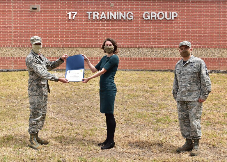 U.S. Air Force Col. Thomas Coakley, 17th Training Group commander, presents the 315th Training Squadron 14N Course Student of the Month award to Ms. Madeline Maclean, 315th TRS student, at Brandenburg Hall on Goodfellow Air Force Base, Texas, May 15, 2020. Military training leaders select top performers each month to be recognized by 17 TRG leadership for their hard work and leadership among their peers. (U.S. Air Force photo by Staff Sgt. Chad Warren)
