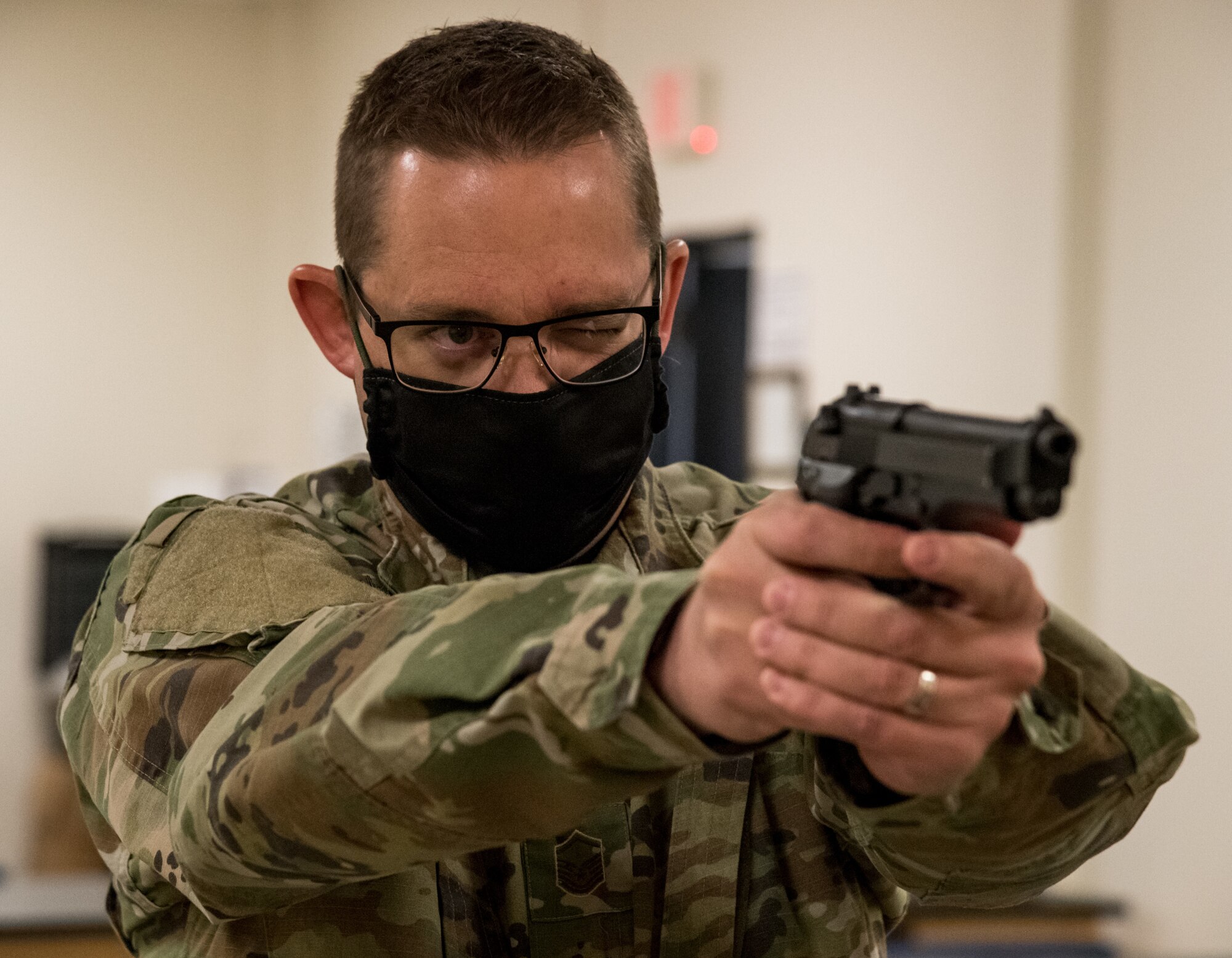 Master Sgt. Jeremy Stupperich, 436th Airlift Wing command post senior emergency actions controller, looks at a target through the M9 sight during Combat Arms Training and Maintenance class May 13, 2020, at Dover Air Force Base, Delaware. Stupperich and other CATM students wore masks whenever six feet of separation could not be maintained, whether in the classroom or on the firing range. A shelter-in-place order was issued in mid-March to help mitigate the spread of COVID-19. (U.S. Air Force photo by Roland Balik)