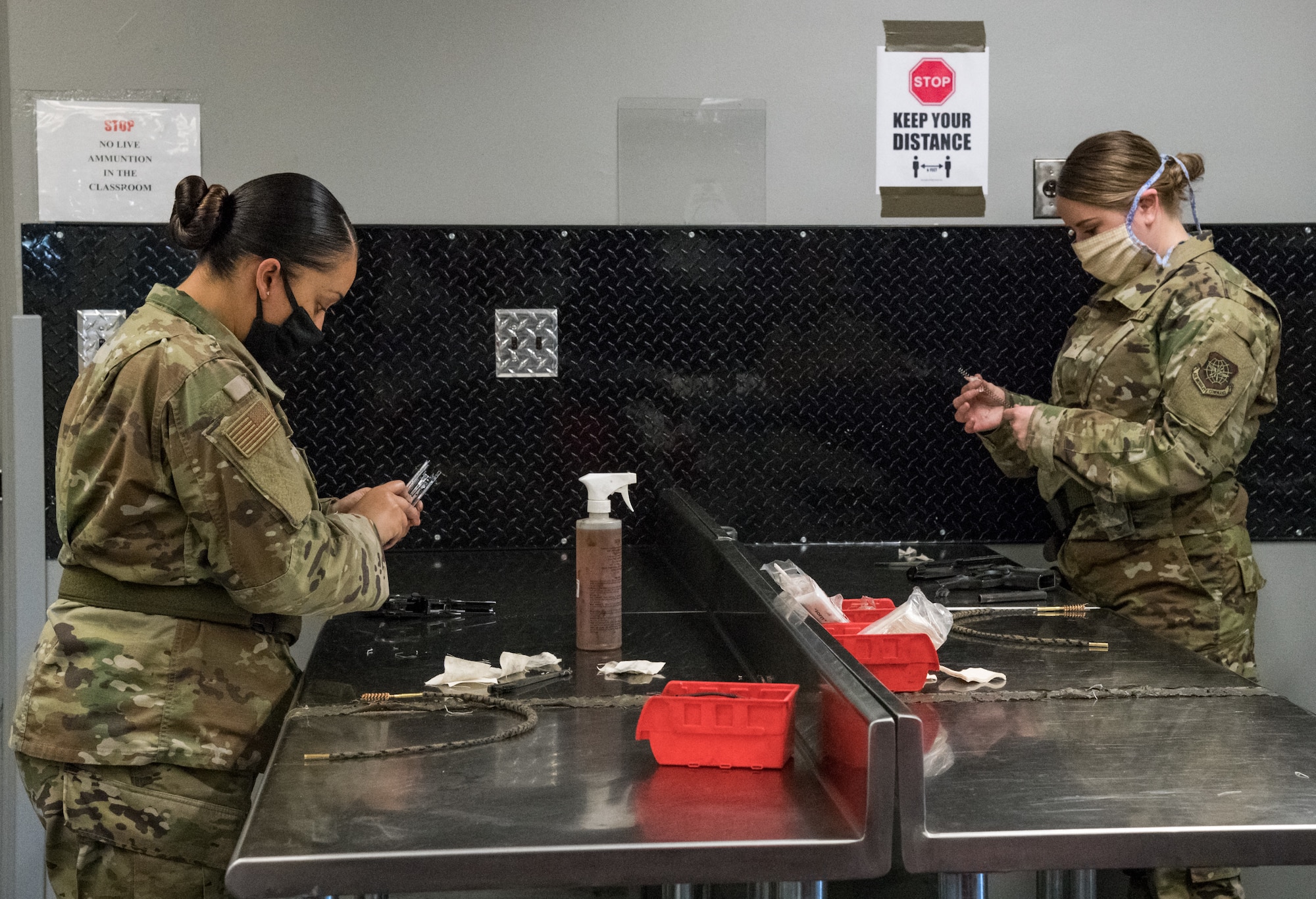 On the left, Staff Sgt. Adrianna Hernandez, 436th Airlift Wing equal opportunity advisor, and Airman 1st Class Kaleigh O’Hara, 436th Comptroller Squadron budget analyst, clean their M9 weapons after qualifying on May 13, 2020, at Dover Air Force Base, Delaware. Hernandez and O’Hara adhered to social distancing guidelines while attending a Combat Arms Training and Maintenance class for the M4 and M9. A shelter-in place order was issued in mid-March to help mitigate the spread of COVID-19. (U.S. Air Force photo by Roland Balik)