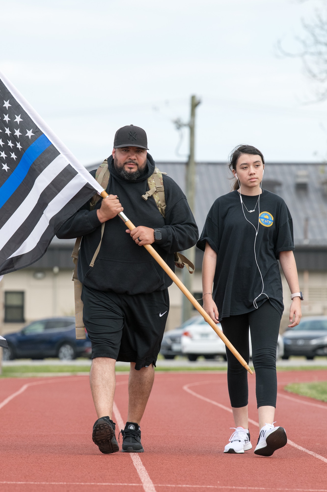 Detective Rafael Gonzalez, 436th Security Forces Squadron, walks with his daughter, Olivia, during the 2020 Police Week Ruck March May 14, 2020, at Dover Air Force Base, Delaware. Gonzalez is carrying a 35-pound ruck on his back and a “Thin Blue Line” version of the American flag, which represents support for law enforcement. (U.S. Air Force photo by Mauricio Campino)