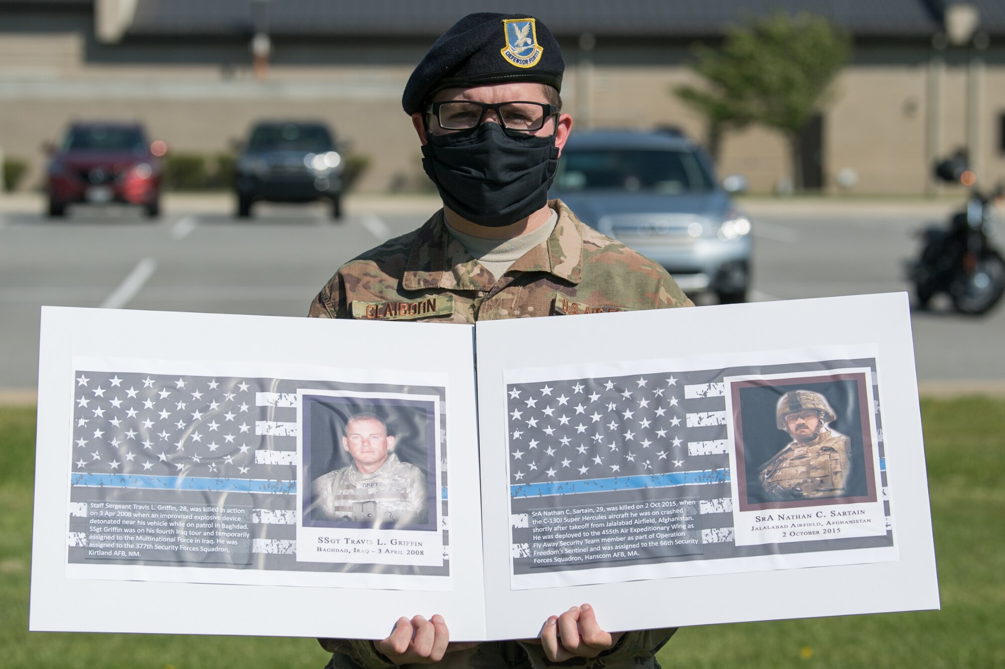 Senior Airman Ryan Claiborn, 436th Security Forces Squadron installation patrolman, holds photos of two fallen defenders during a retreat ceremony on Peace Officers Memorial Day May 15, 2020, at Dover Air Force Base, Delaware. The ceremony commemorating fallen military and civilian law enforcement officers marked the end of National Police Week 2020. (U.S. Air Force photo by Mauricio Campino)