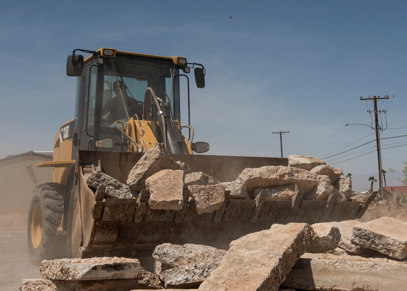 A RED HORSE Airman utilizes a loader to lift and move rocks.