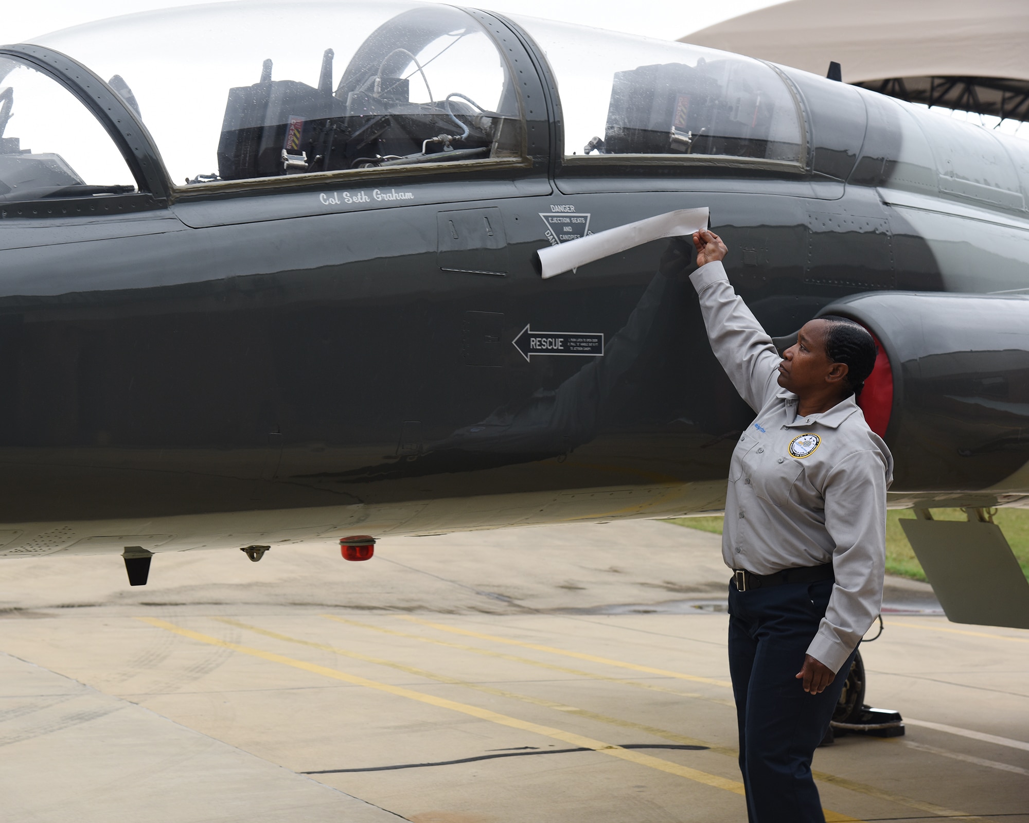 An M1 Support Services technician reveals the name of Col. Seth Graham, 14th Flying Training Wing commander, on the Blaze 1, a T-38 Talon, on May 18, 2020 at Columbus Air Force Base, Miss. Each commander has an aircraft with their name painted across the side. (U.S. Air Force photo by Elizabeth Owens)