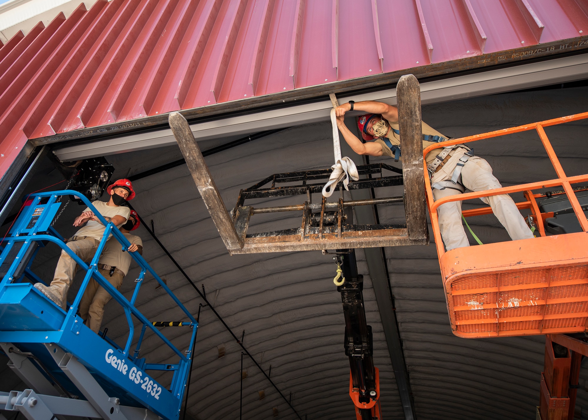 RED HORSE Airmen utilize heavy equipment to install a roll-up door.