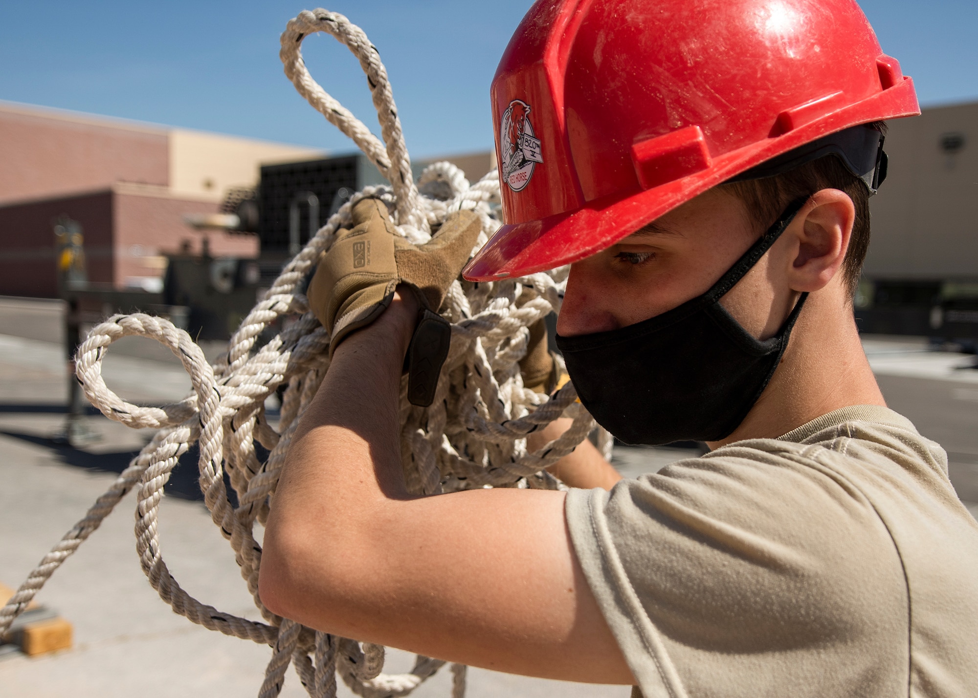 A RED HORSE Airman carries rope over his shoulder.