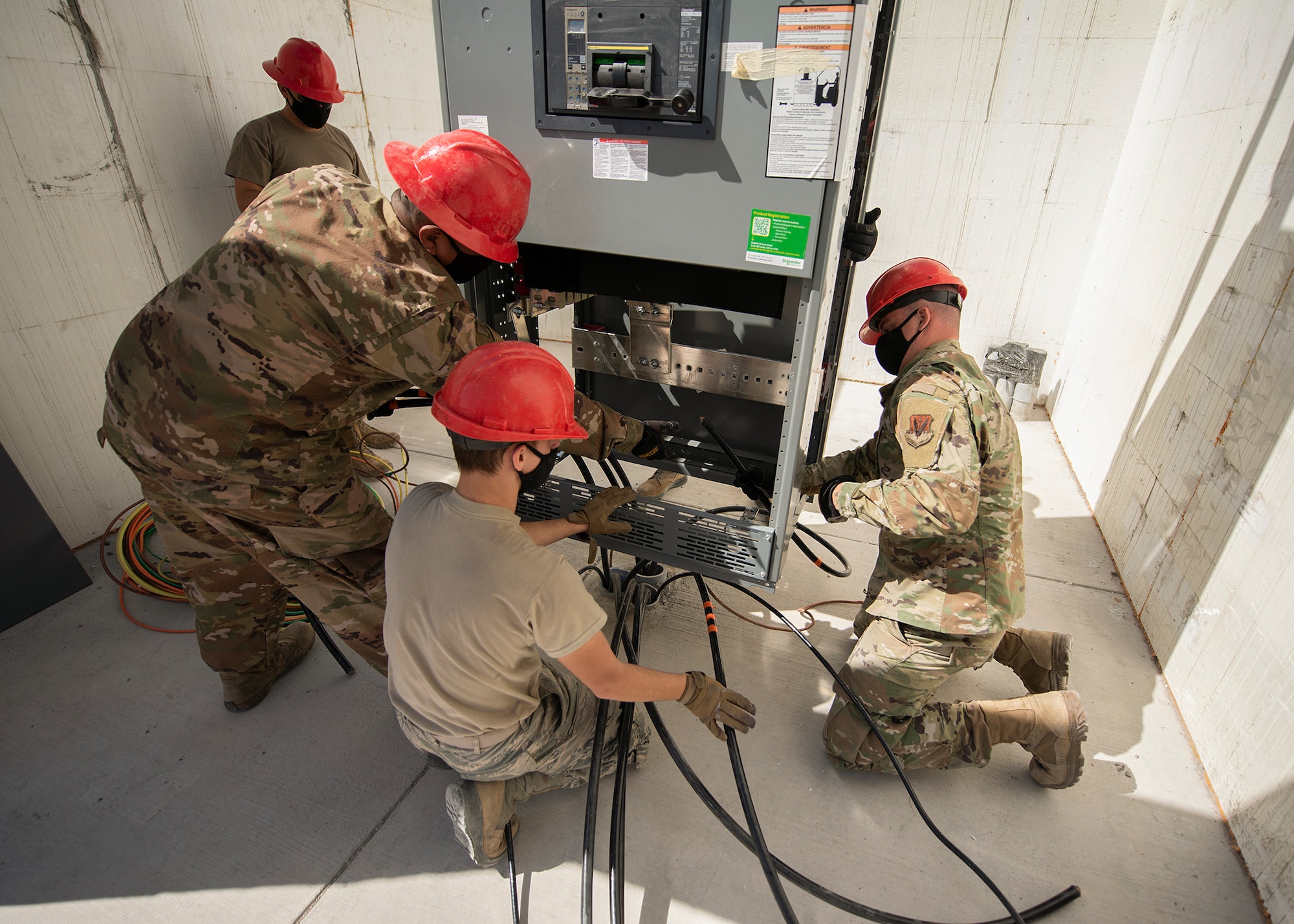 Four RED HORSE Airmen guide a gearbox into position.