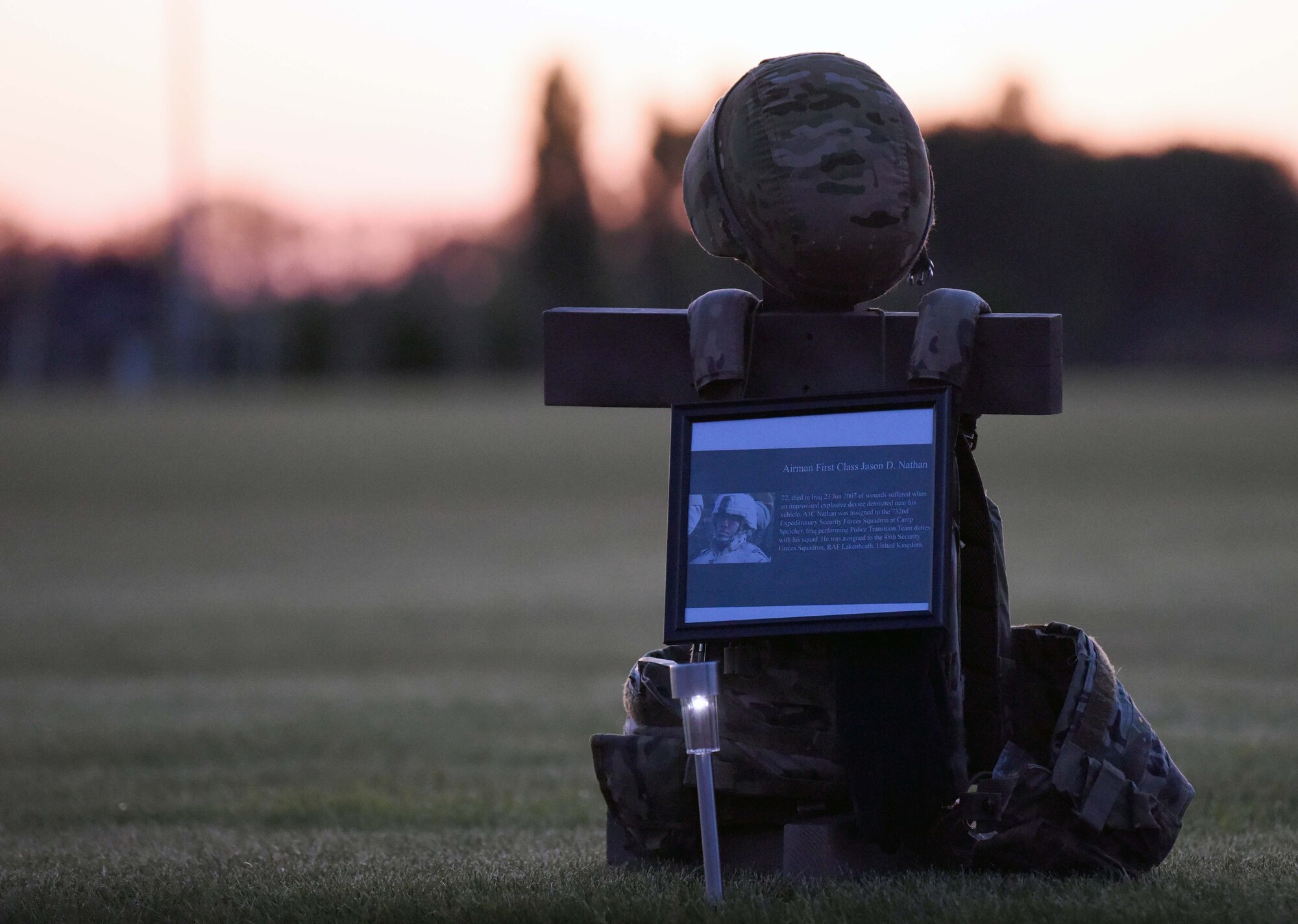 A memorial display for Airman 1st Class Jason D. Nathan rests during a candlelight vigil to honor the “Fallen 14” during events to commemorate National Police Week at RAF Mildenhall, England, May 14, 2020. Nathan, a former 48th Security Forces Squadron Airman, died in Iraq in 2007 from wounds suffered from an IED that detonated near his vehicle. (US. Air Force photo by Senior Airman Brandon Esau)