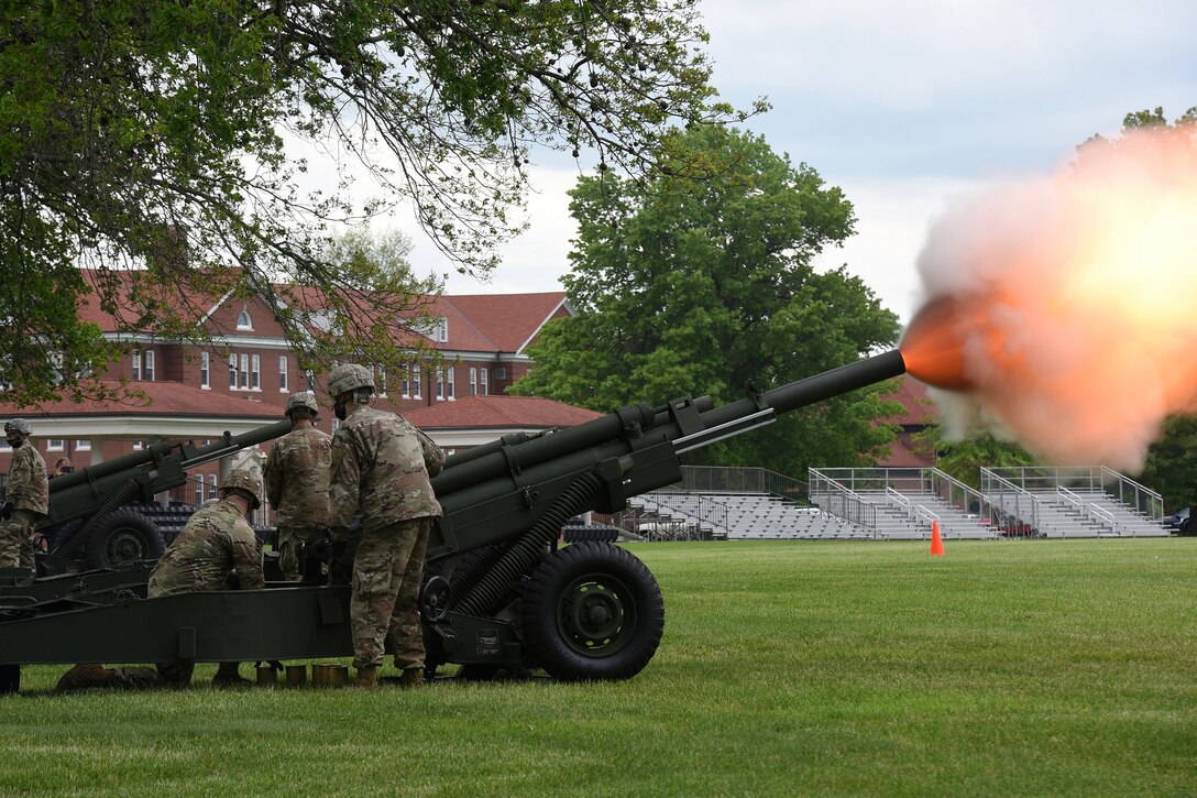 Soldiers fire a cannon on a large field.