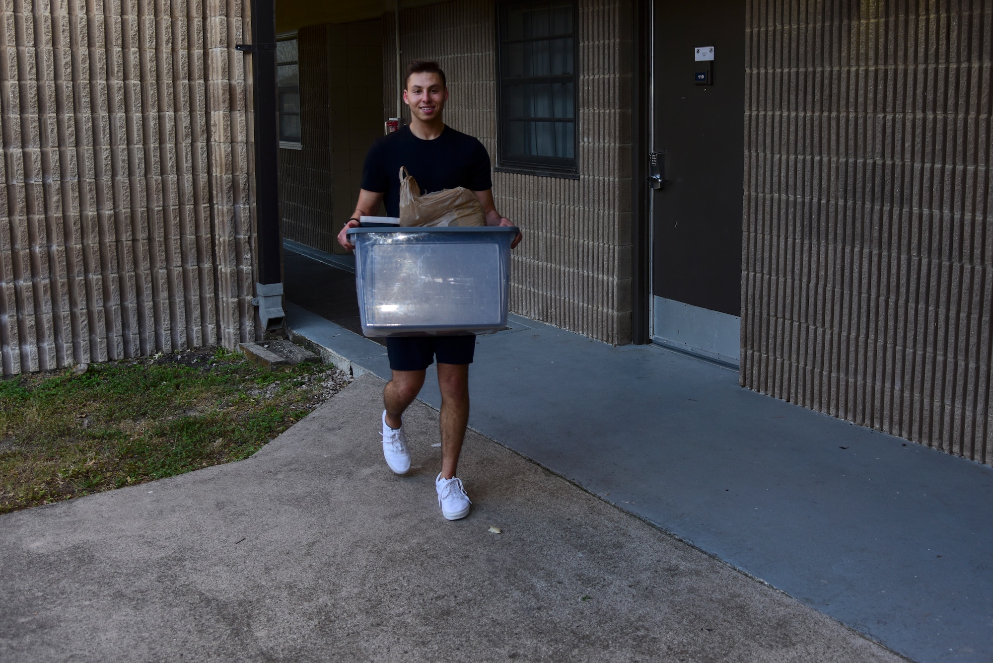 Airman 1st Class Matthew Blasberg, 47th Healthcare Operations Squadron referral management and patient travel technician, walks down from his dorm room with a container of cooking supplies, May 5, 2020 at Laughlin Air Force Base, Texas. For Blasberg, the trouble of cooking five or so meals at a time is well-worth the effort because of the time it saves him time in the long run. (U.S. Air Force photo by Senior Airman Anne McCready)