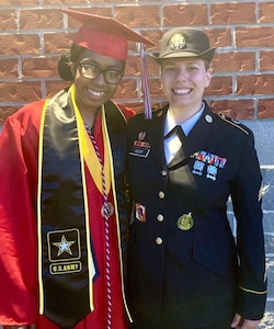 Future Soldier dressed in graduation cap and gown poses with female Soldier, Sgt. Mort, who is wear her Army dress uniform.