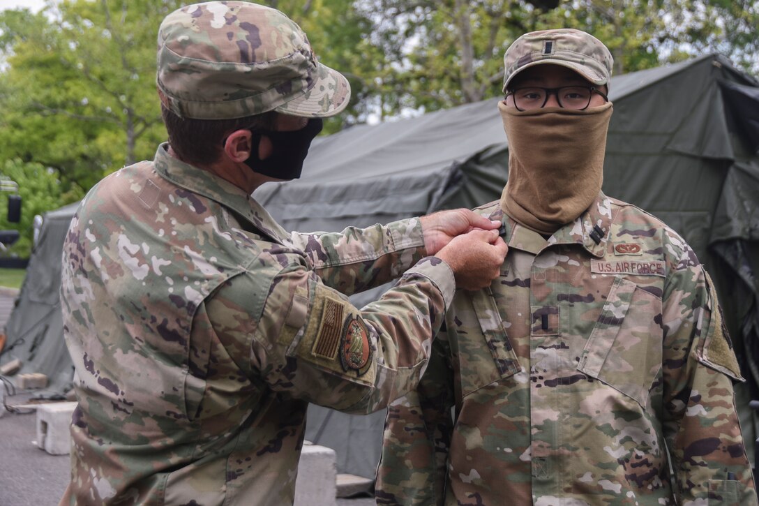U.S. Air Force Col. John Cosgrove, 108th Wing commander, left, pins captain ranks on 1st Lt. Jiahua Ye during a promotion ceremony at the Union County COVID-19 testing site located at Kean University in Union, N.J., May 18, 2020.  Ye is serving as the officer in charge of the testing site and is responsible for ensuring the Guardsmen’s needs are met in order to accomplish the mission. (U.S. Air National Guard photo by Senior Airman Julia Santiago)