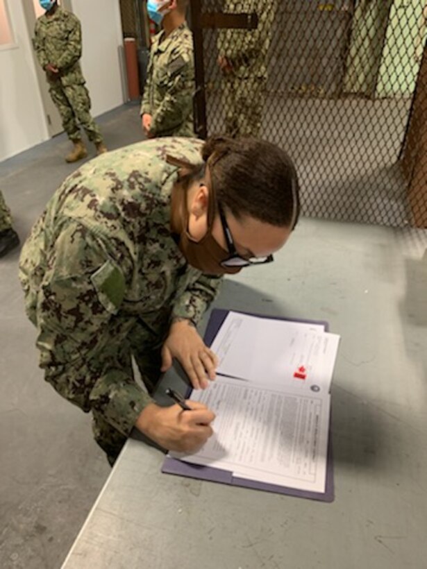 Sailor signing paperwork on a table.