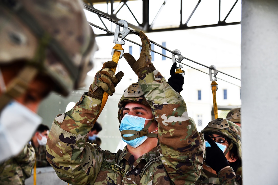 Army paratroopers wearing face masks practice jump preparations.