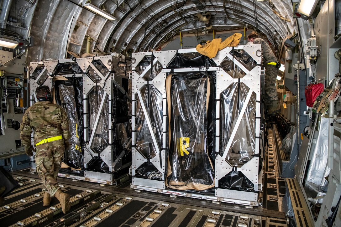 Airmen cover a Transport Isolation System with a tarp.