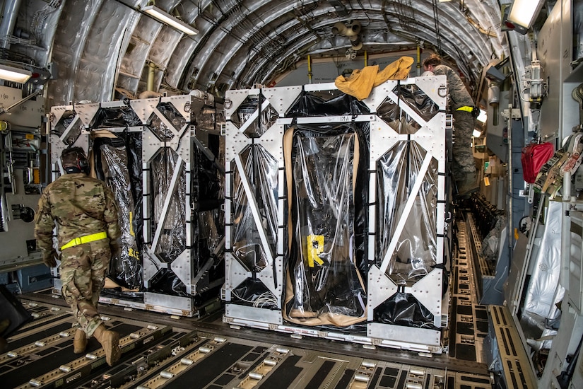 Airmen cover a Transport Isolation System with a tarp.