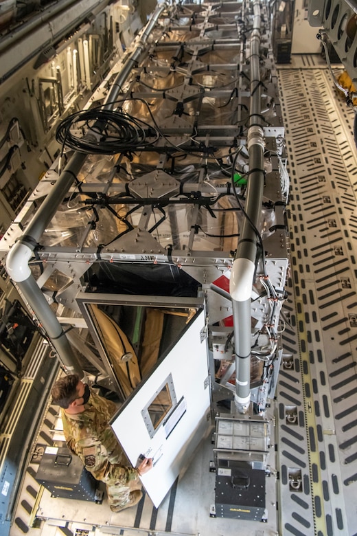 An airman opening the door to a Transport Isolation System.