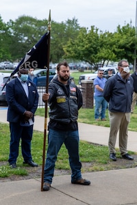 Norfolk Naval Shipyard (NNSY) Veteran Employee Readiness Group (VET-ERG) Information and Awareness Officer Nate Benton stands ready with the VET-ERG flag during the Memorial Day Fall-In for Colors May 19.