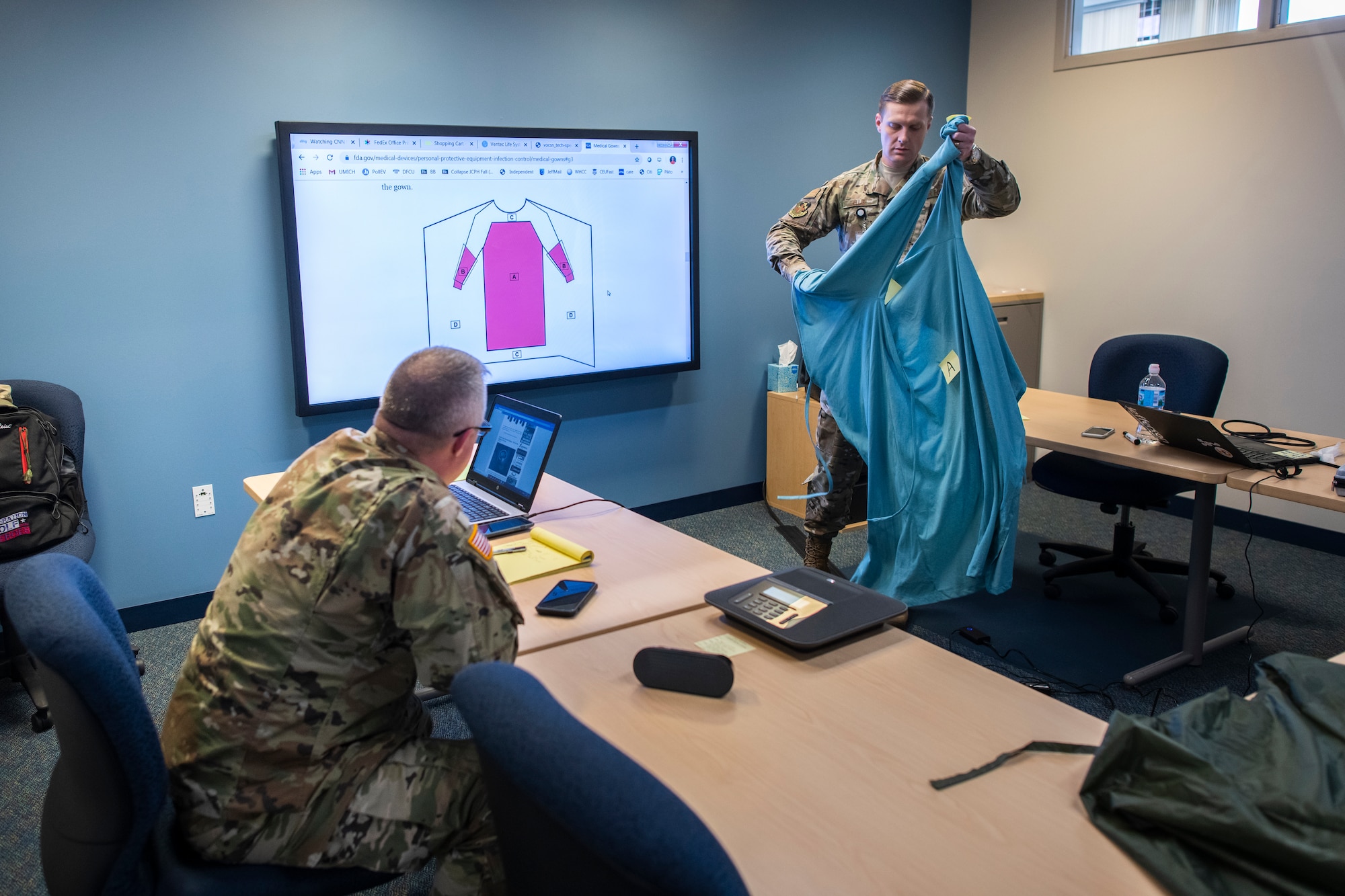 U.S. Air Force Capt. Brynt Ellis, medical readiness officer of the 127th Medical Group, Selfridge Air National Guard Base, Michigan,tests a prototype protective gown while working with Army Command Sgt. Maj. Kevin Palmatier, garrison command sergeant major of Camp Grayling, to procure products for clinicians combating the COVID-19 pandemic.