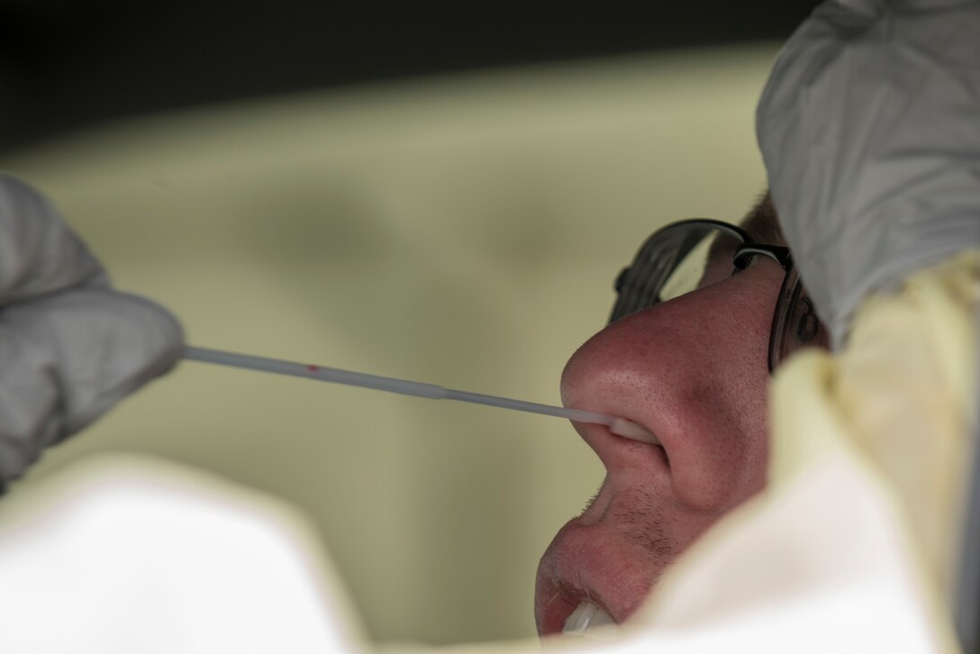 a hand guides a swab out of a nose