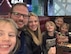 A husband and wife pose with their four young children at a restaurant.