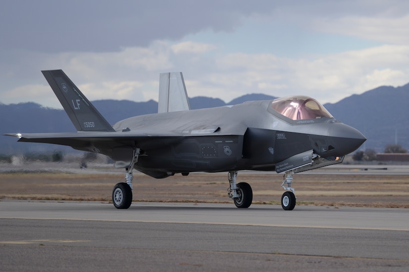 A military aircraft moves across a runway.