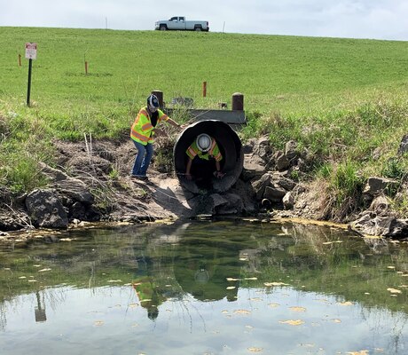 Narturi Narciso, engineer in training, U.S. Army Corps of Engineers, Omaha District, exits a conduit at Salt Creek Site 2, Olive Creek Dam, Neb., after conducting a structural inspection May 1. Kristle Beaudet, dam safety manager, assists with the equipment and documentation. This was the first inspection the dam safety program conducted since the COVID-19 pandemic began.