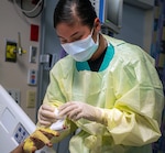 Pvt. Sage Deemer, a combat medic specialist temporarily assigned to the U.S. Army Institute of Surgical Research Burn Center applies bandages and gauze to a burn patient.