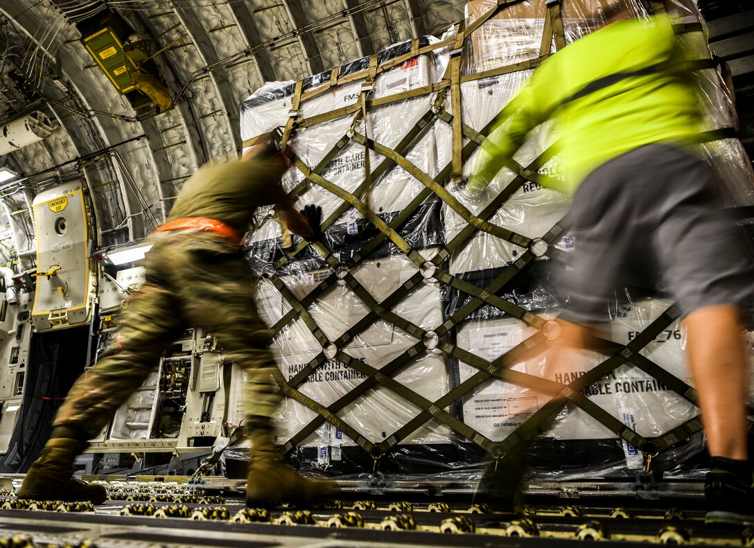 Two men position a pallet of boxes inside an aircraft