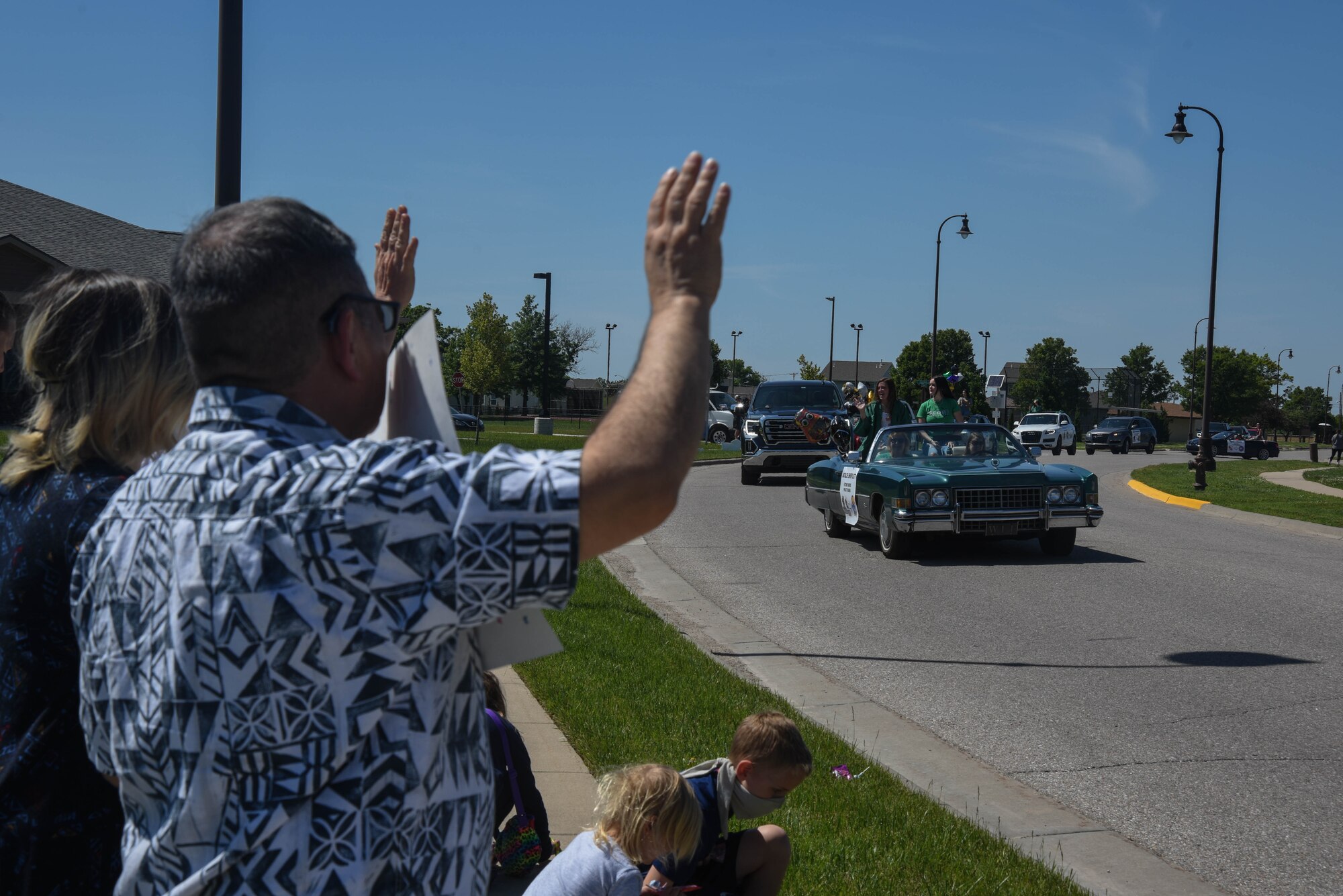 Parade spectators celebrate the graduates as they watch the parade pass through neighborhood streets May 18, 2020, at McConnell Air Force Base, Kansas. Families on base housing decorated drive ways, made congratulatory signs and cheered graduates as they toured through base housing. (U.S. Air Force photo by Airman 1st Class Marc A. Garcia)