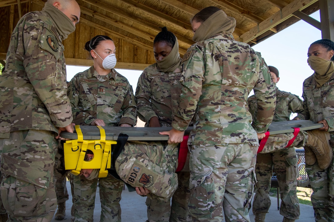 Airmen hold a man on a spinal board