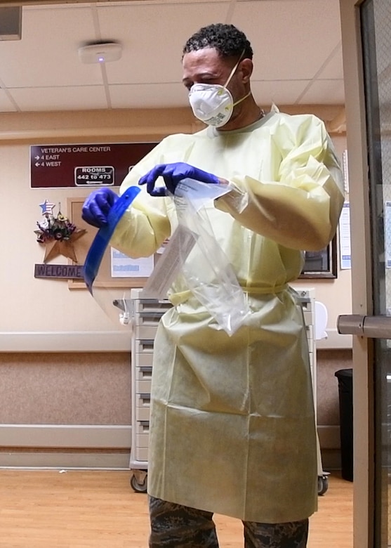 An Air Force chaplain puts on personal protective equipment.
