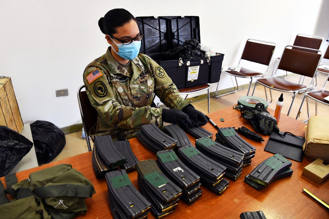 A soldier wearing a mask loads magazines.