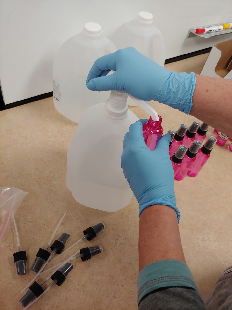 A technician fills hand sanitizer bottles.