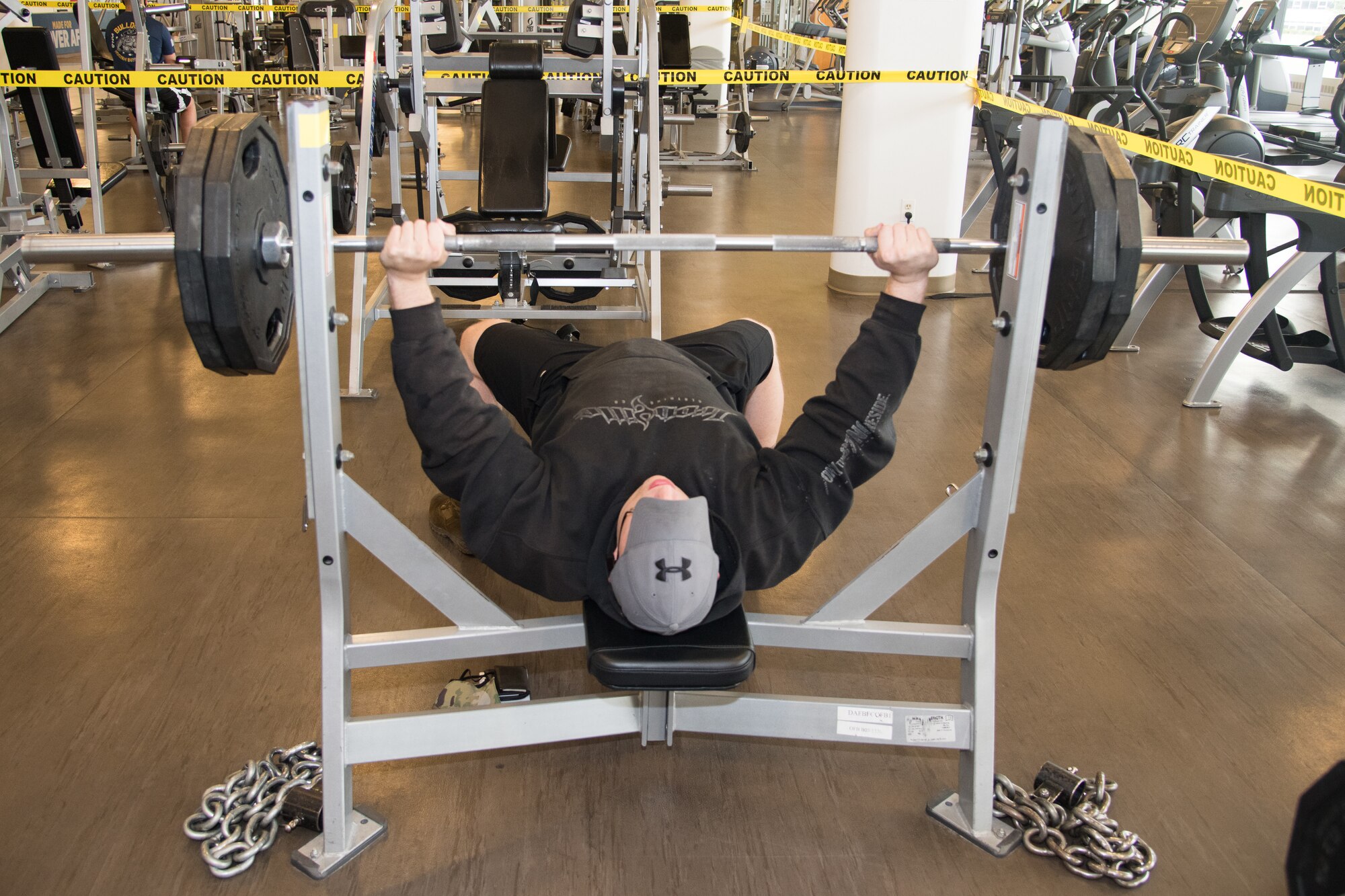 Tech Sgt. Matt Tira, 512th Maintenance Squadron Squadron hydraulic systems craftsman, finishes a set of bench presses at the fitness center, May20, 2020, at Dover Air Force Base, Delaware. Various sections of the fitness center have been separated by caution tape to help minimize crowding and encourage social distancing. (U.S. Air Force photo by Airman 1st Class Faith Schaefer)