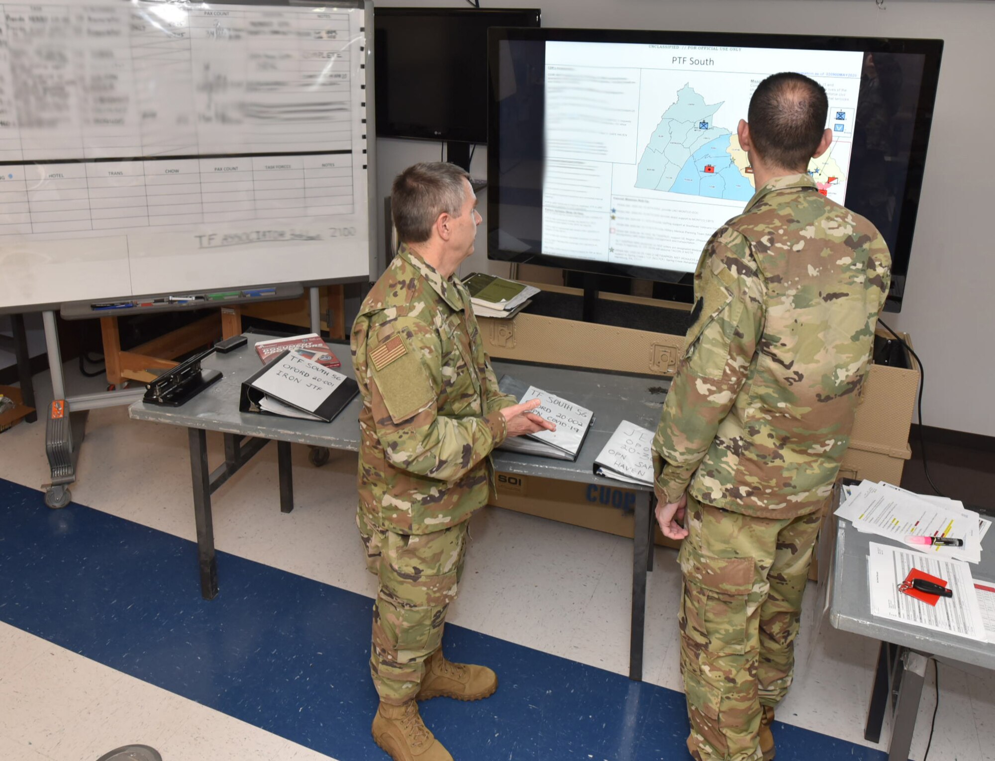 Col. Scott Coradi, left, and Col. Jon Farr discuss operational plans while overlooking a map of the area of operations for Pennsylvania Task Force South at Horsham Air Guard Station, Pennsylvania, May 2, 2020.