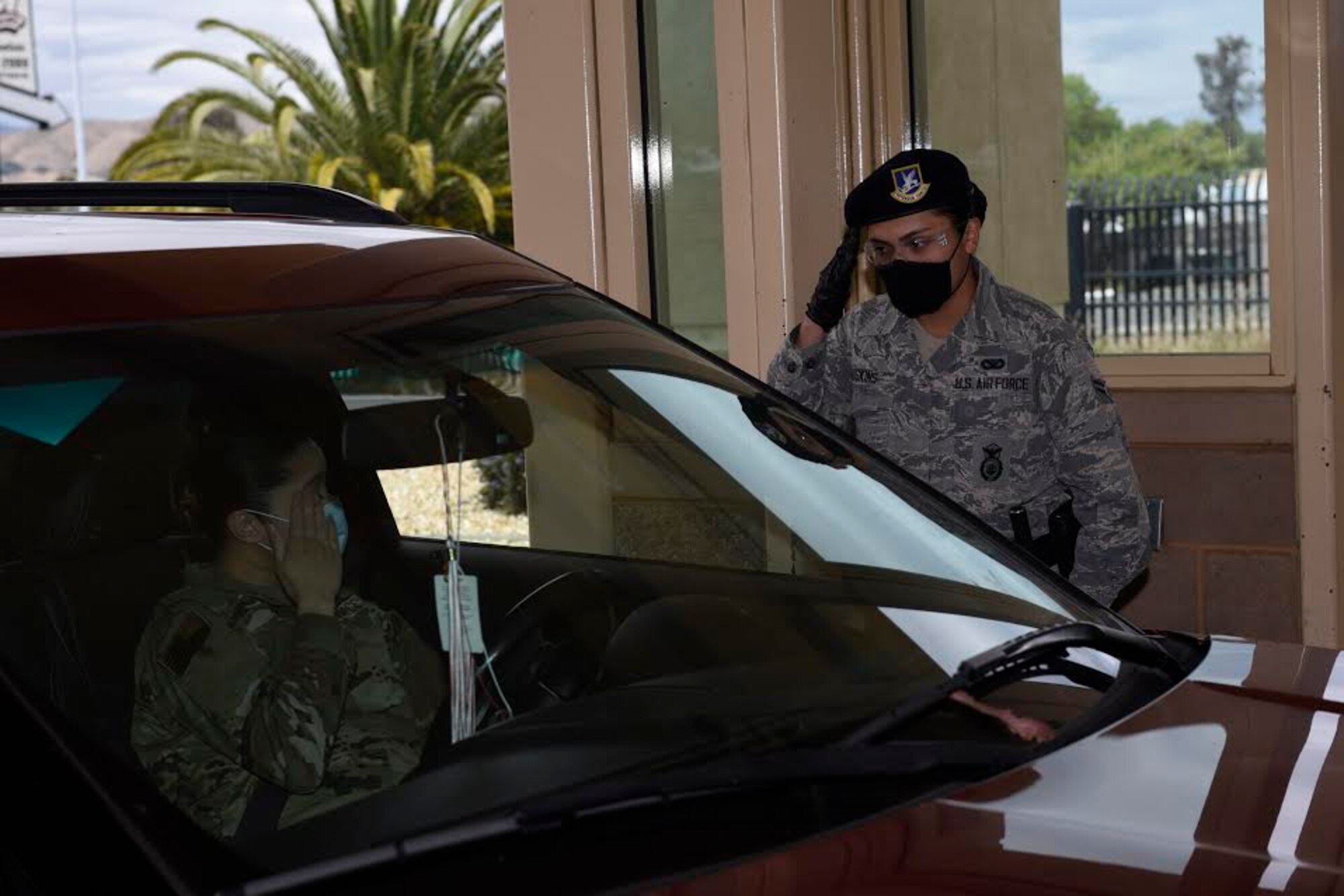 U.S. Air Force Airman 1st Class Hannah Hoskins, 60th Security Forces Squadron entry controller, salutes an officer May 11, 2020, at the main gate of Travis Air Force Base, California. Security forces Airmen manning entry control points at Travis AFB are required to wear protective equipment such as masks and gloves to prevent exposure to the coronavirus. (U.S. Air Force photo by Airman 1st Class Cameron Otte)