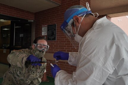 U.S. Army Spc. Tamra Townsend, a combat medic specialist, cuts a sterile swab stick at Diaz - Villarreal Elementary School in Mission, Texas, May 4, 2020. The Texas Military Department is supporting the critical health care infrastructure and assisting with mobile testing for COVID-19.