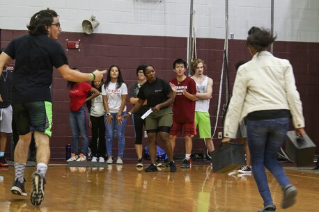 Staff Sgt. Lindsay Johnson, a Marine Corps recruiter with Recruiting Substation Pensacola, motivates a student during an ammo can run during the USMC Sports Leadership Academy aboard Pensacola High School, Pensacola, Florida, Oct. 24, 2019. The purpose of the academy is to create events that promote physical readiness and leadership training. (U.S. Marine Corps photo by Cpl. Terry Haynes)